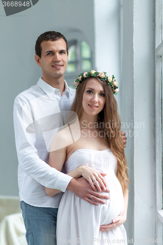 Image of Cheerful young couple  dressed in white standing at home