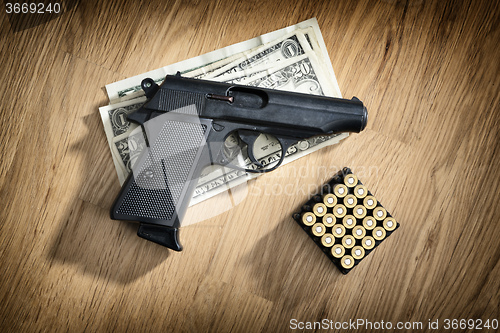 Image of pistol with cartridges and dollar notes