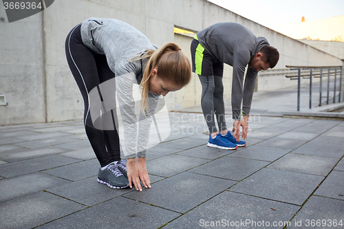 Image of couple stretching and bending forward on street