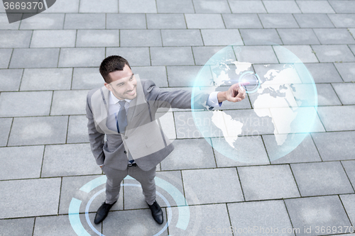 Image of smiling businessman with globe projection outdoors