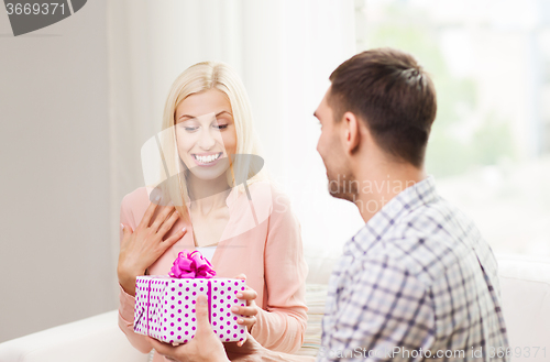 Image of happy man giving woman gift box at home