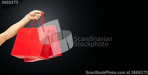 Image of close up of hand holding red shopping bags