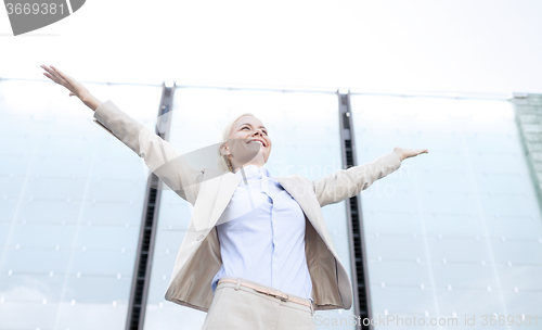 Image of young smiling businesswoman over office building