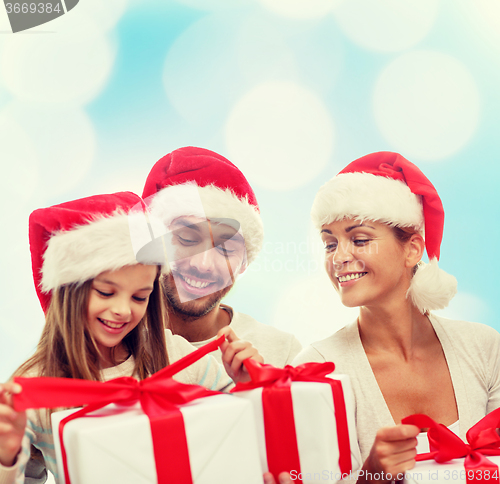 Image of happy family in santa helper hats with gift boxes