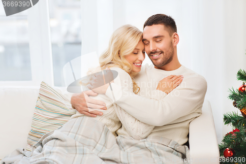Image of happy couple hugging on sofa at home