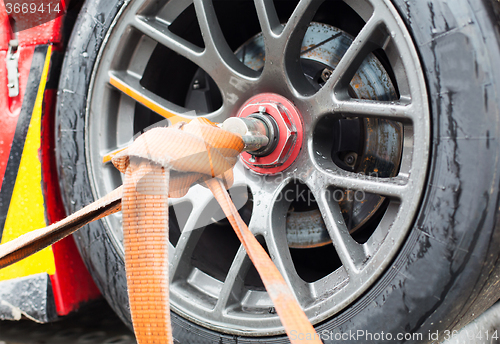 Image of close up of race car wheel with tow rope tied to