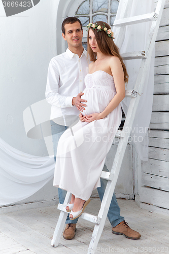 Image of Cheerful young couple  dressed in white standing at home