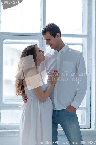 Image of Cheerful young couple  dressed in white sitting on sofa 