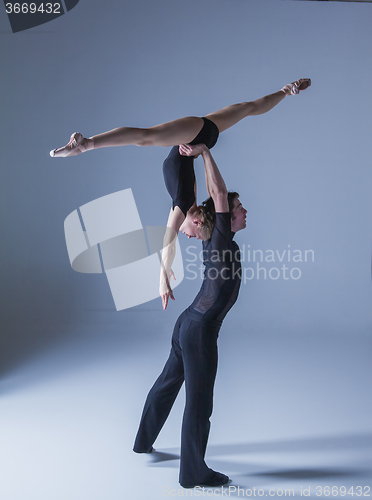 Image of two young modern ballet dancers on blue studio background 