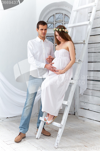 Image of Cheerful young couple  dressed in white standing at home