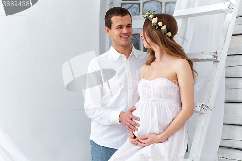 Image of Cheerful young couple  dressed in white standing at home