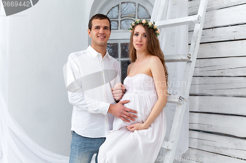 Image of Cheerful young couple  dressed in white standing at home