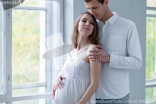 Image of Cheerful young couple  dressed in white sitting on sofa 