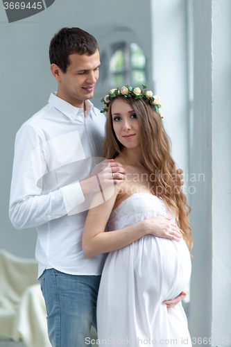 Image of Cheerful young couple  dressed in white standing at home