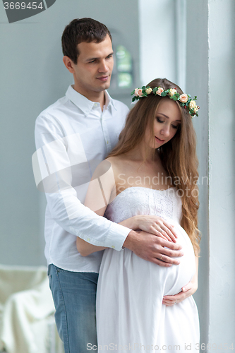 Image of Cheerful young couple  dressed in white standing at home