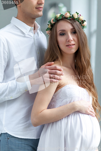 Image of Cheerful young couple  dressed in white standing at home