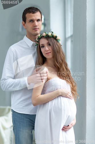 Image of Cheerful young couple  dressed in white standing at home