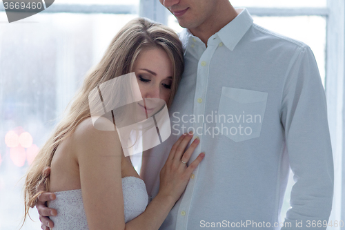 Image of Cheerful young couple  dressed in white sitting on sofa 