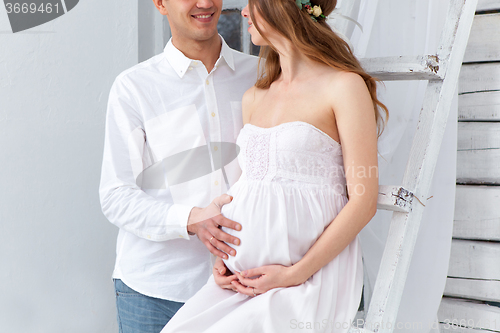 Image of Cheerful young couple  dressed in white sitting on sofa 