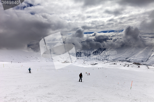 Image of Skiers on ski slope before rain