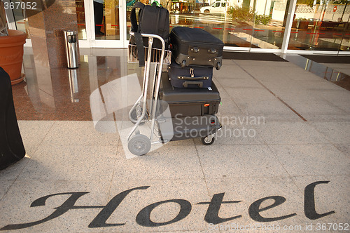 Image of Suitcases and trolley in front of hotel