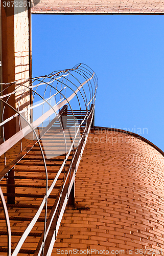 Image of Industrial ladder, blue sky and brick walls of the building