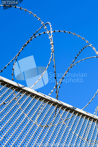 Image of Fence with a barbed wire against the blue sky. 