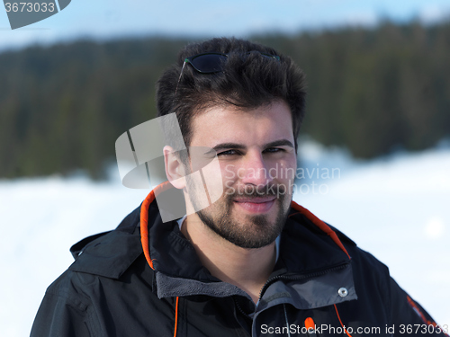 Image of portrait of young man with beard and sunglasses on fresh snow