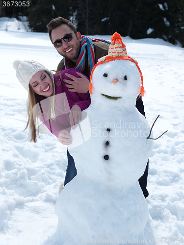 Image of portrait of happy young couple with snowman