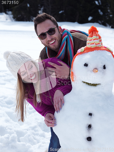 Image of portrait of happy young couple with snowman