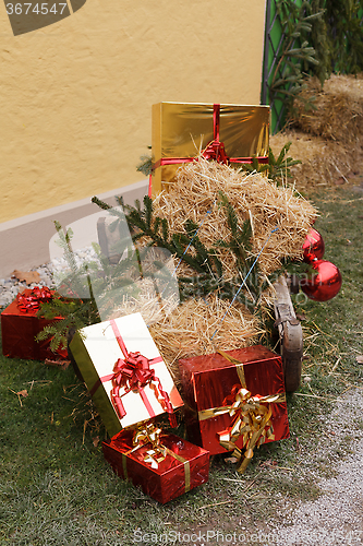 Image of Christmas packages with straw and pine branches on a sled