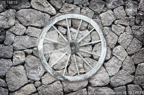 Image of Wooden wagon wheel on a stone back ground.
