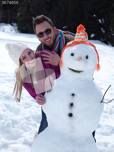 Image of portrait of happy young couple with snowman