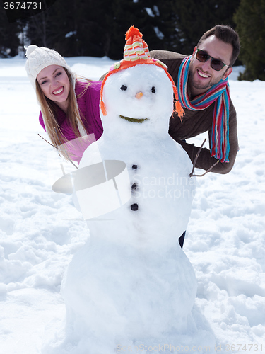 Image of portrait of happy young couple with snowman