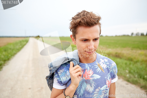 Image of sad young hippie man walking along country road