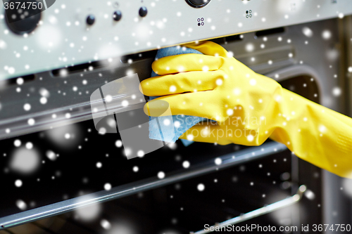 Image of close up of woman cleaning oven at home kitchen