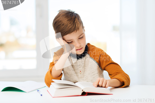 Image of student boy reading book or textbook at home