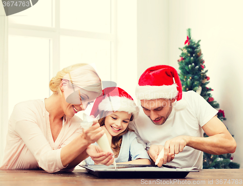 Image of happy family in santa helper hats cooking