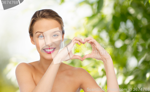 Image of smiling young woman showing heart shape hand sign