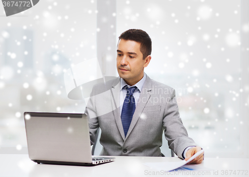 Image of businessman with laptop and papers