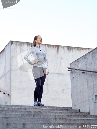 Image of smiling sportive woman on stairs at city