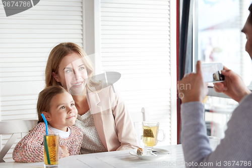 Image of happy family picturing by smartphone at restaurant