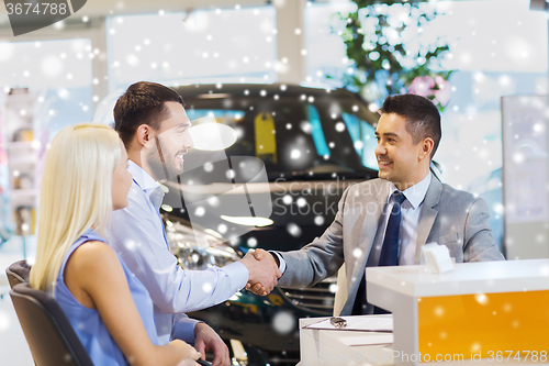 Image of happy couple making deal with car dealer at salon