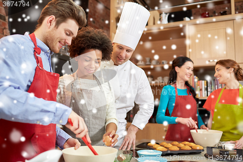 Image of happy friends and chef cook baking in kitchen