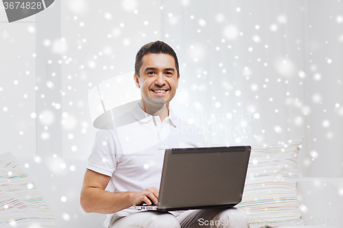 Image of happy man working with laptop computer at home