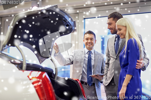 Image of happy couple with car dealer in auto show or salon