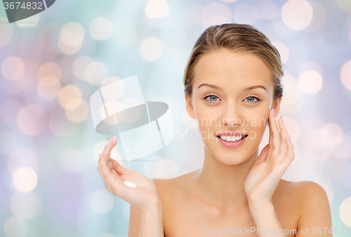 Image of happy young woman applying cream to her face