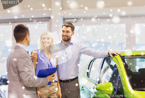 Image of happy couple with car dealer in auto show or salon