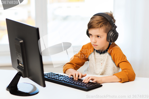 Image of boy with computer and headphones at home