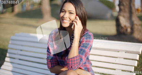 Image of Woman Using Cell Phone On Park Bench
